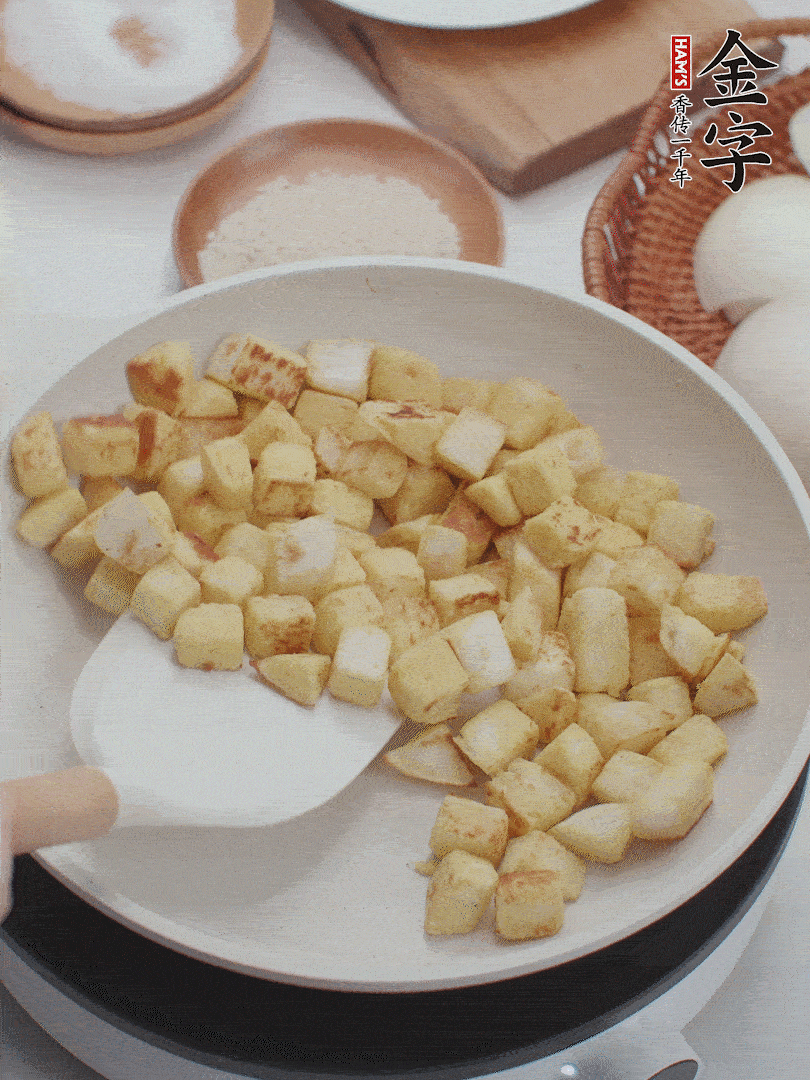 起鍋熱油，倒入饅頭丁，小火煎至蛋液凝固定型再翻面，饅頭丁部煎至金黃時(shí)盛起待用。