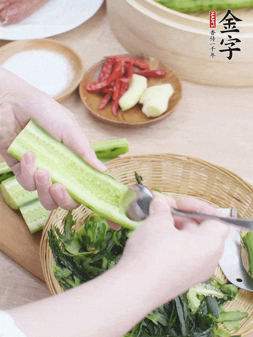 黃瓜削皮，對半切開，勺子挖去內(nèi)瓤，斜刀切片。青蒜斜刀切段。